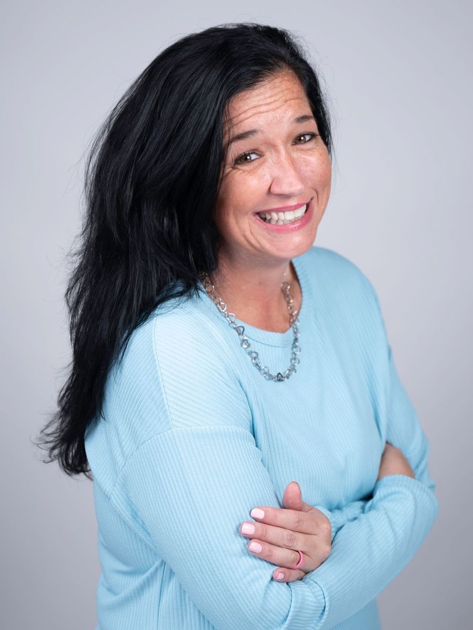 A woman is smiling while sitting at a desk in front of a computer.