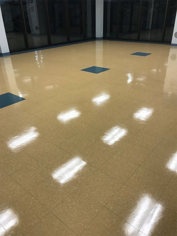 Empty polished hallway floor with bright light reflections and blue square tiles near glass windows