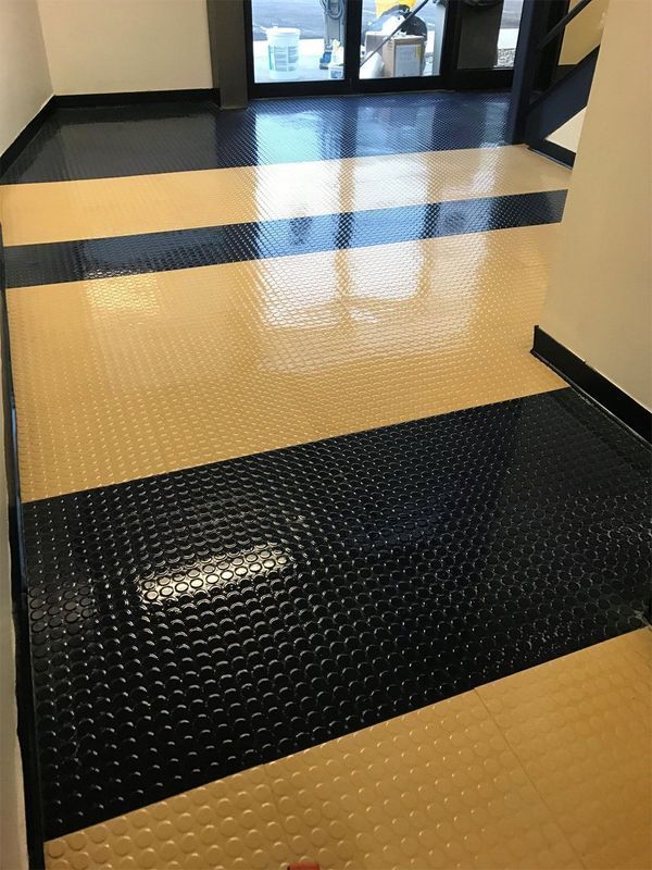Hallway with black and yellow textured floor tiles leading to glass doors