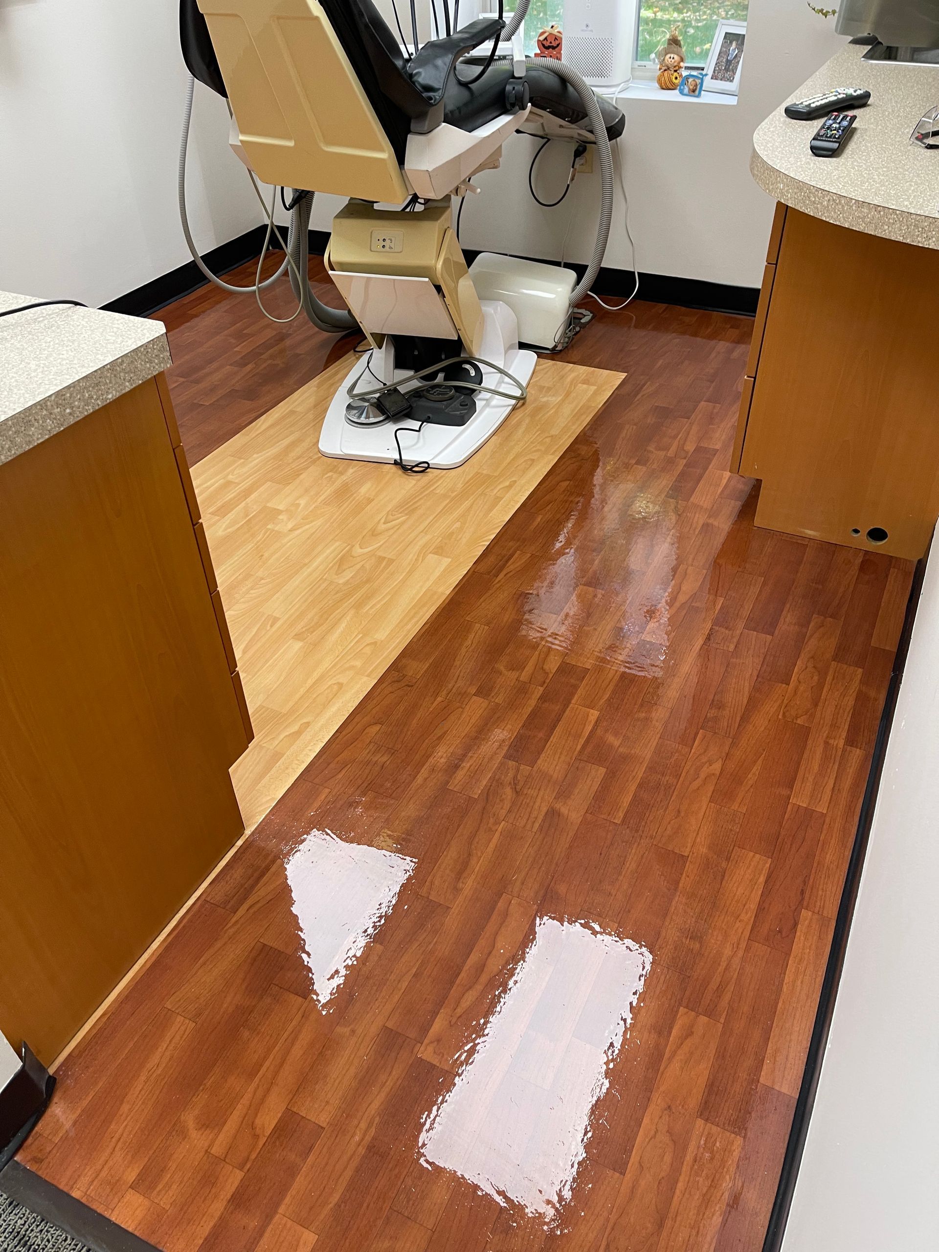 A medical examination room with a chair, featuring two white shapes painted on the dark wood-look floor.