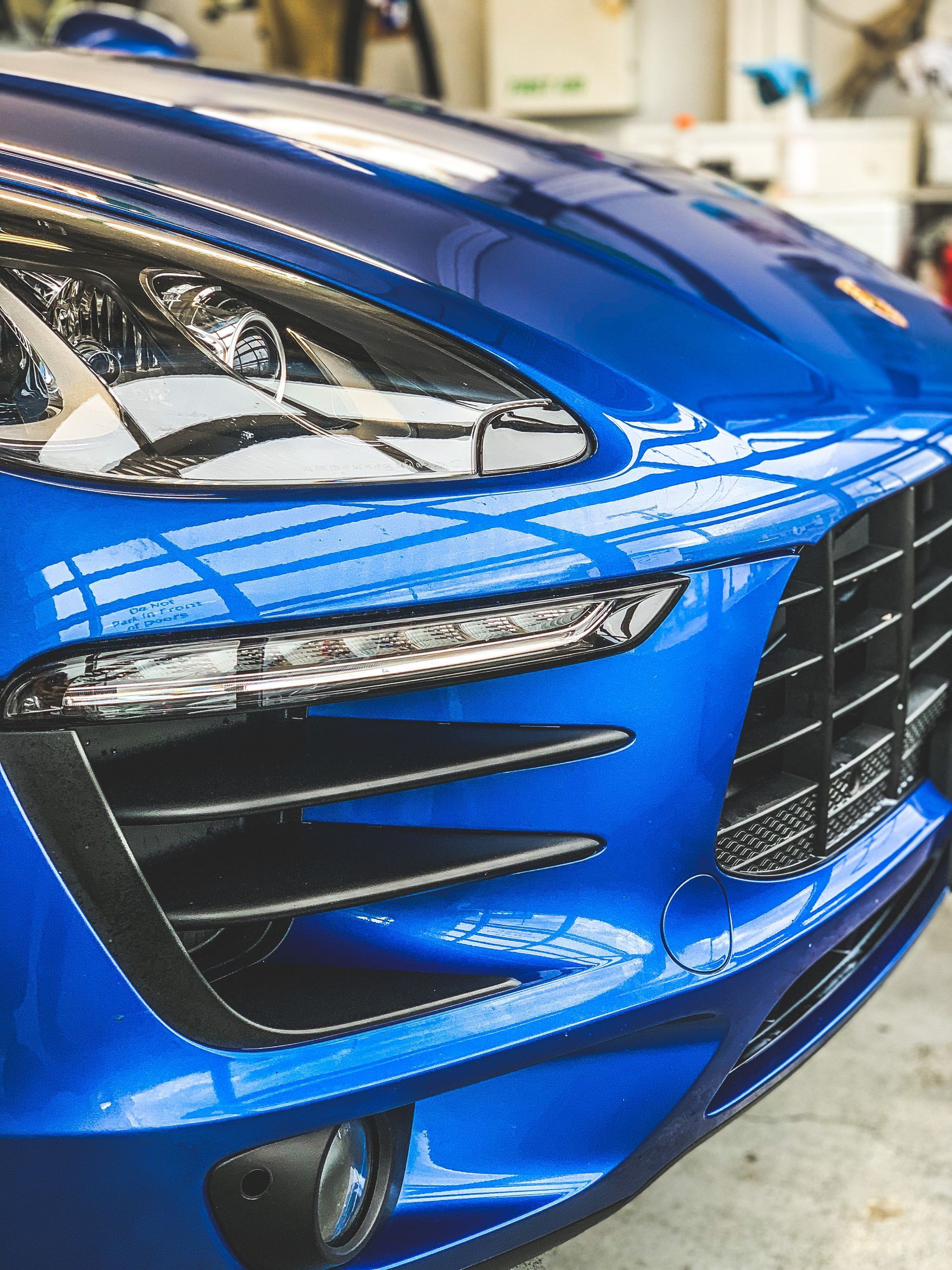 Blue Porsche car front with headlight and grill.
