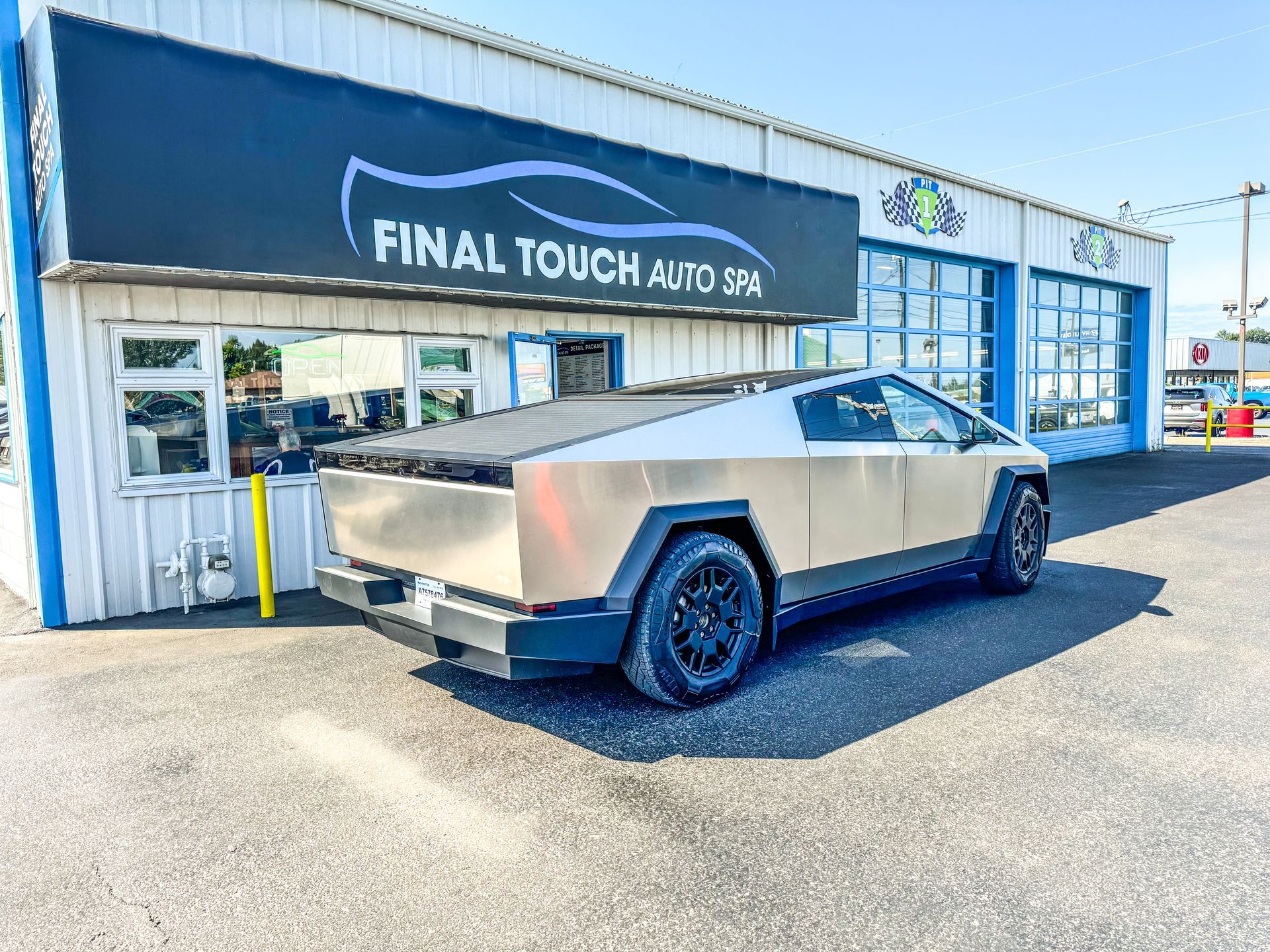 Tesla Cybertruck parked in front of Final Touch Auto Spa with a gray and tan body.