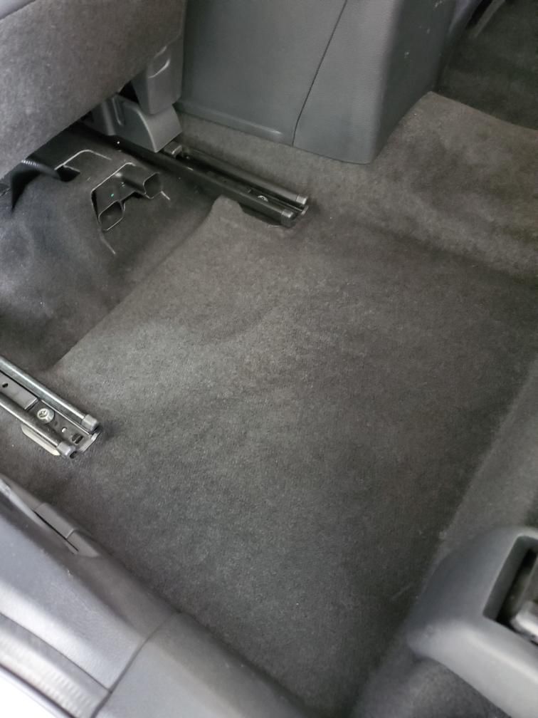 Gray car carpet with visible seat rails and console.