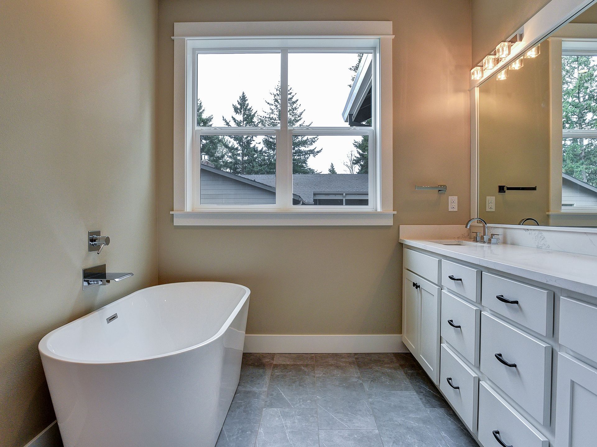A bathroom with a tub , sink , mirror and window