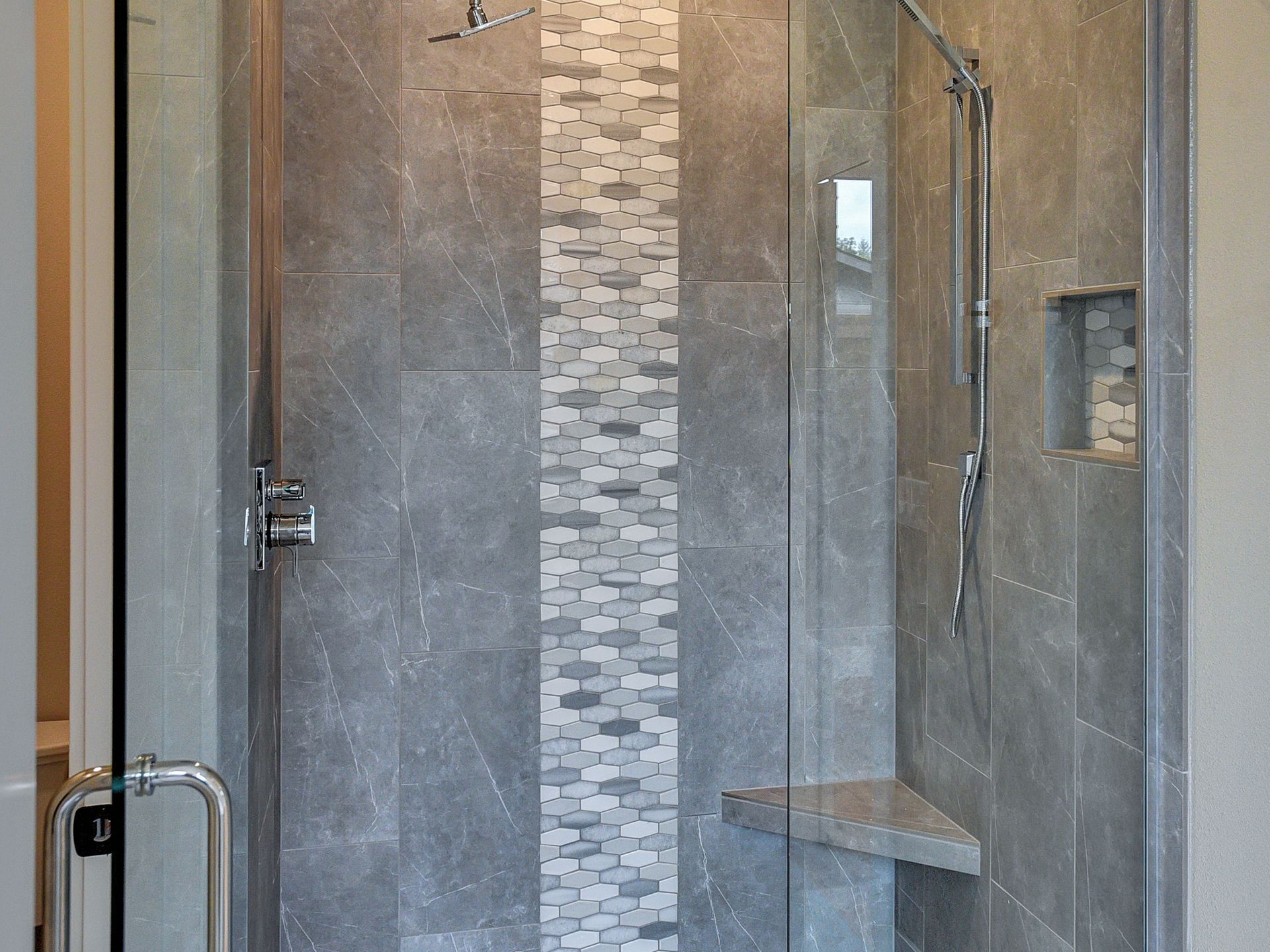 A bathroom with a walk in shower with a glass door.