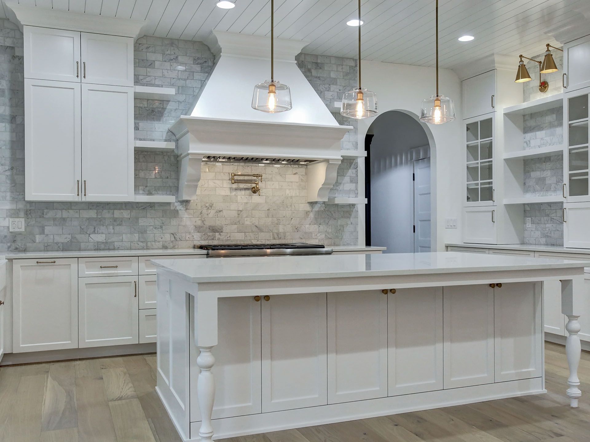 A kitchen with white cabinets and a large island in the middle.