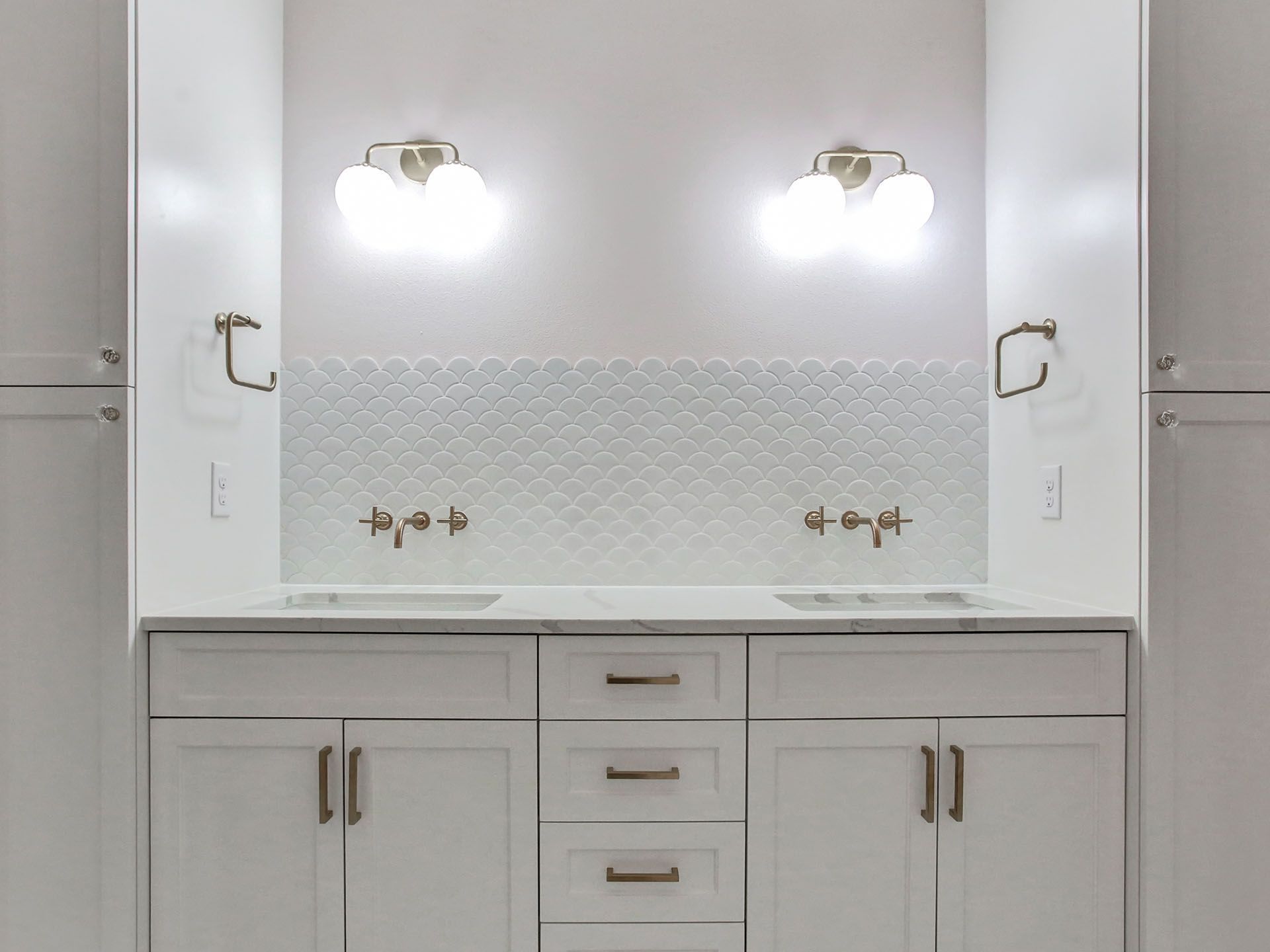 A bathroom vanity with two sinks and two lights on the wall.