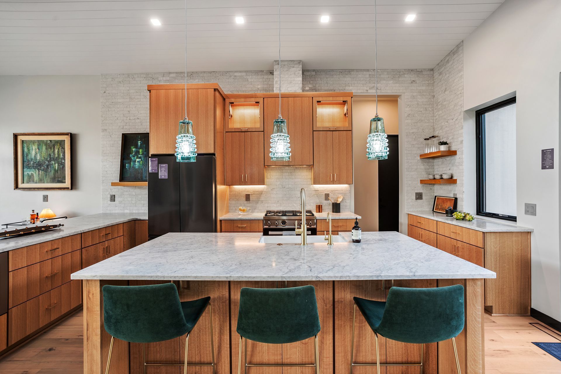 A kitchen with a large island and three green chairs.