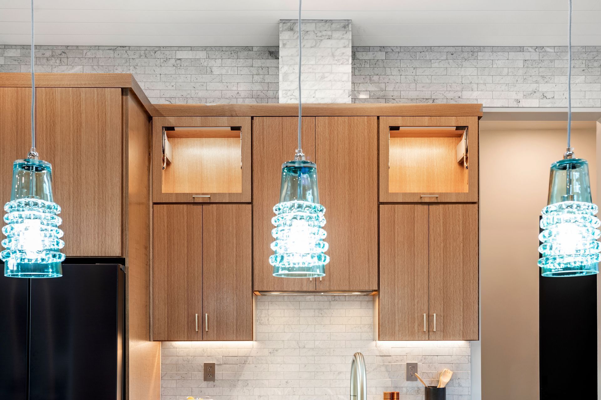 A kitchen with wooden cabinets and blue pendant lights