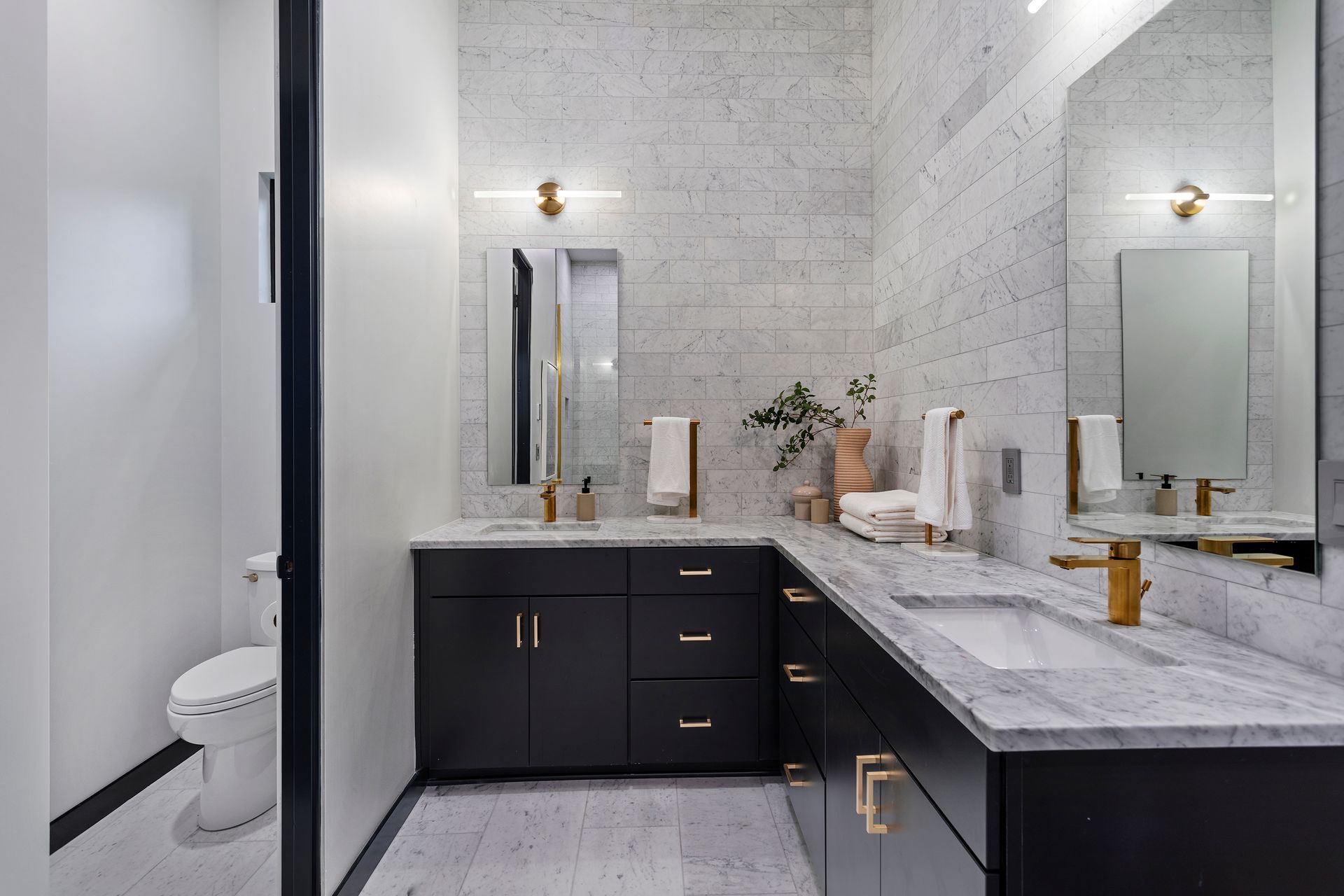 A bathroom with two sinks , a toilet and a mirror.