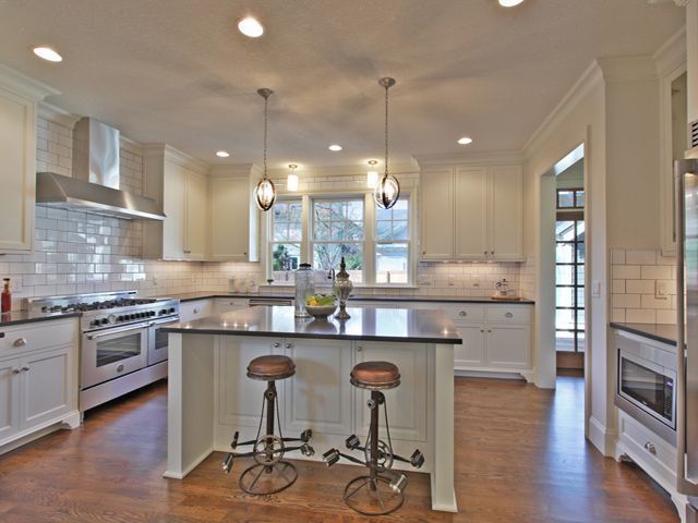 A kitchen with white cabinets and stools and a large island
