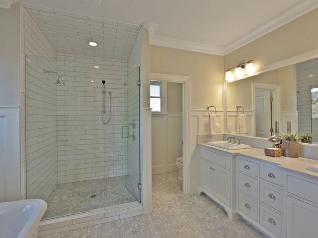 A bathroom with a walk in shower and two sinks.