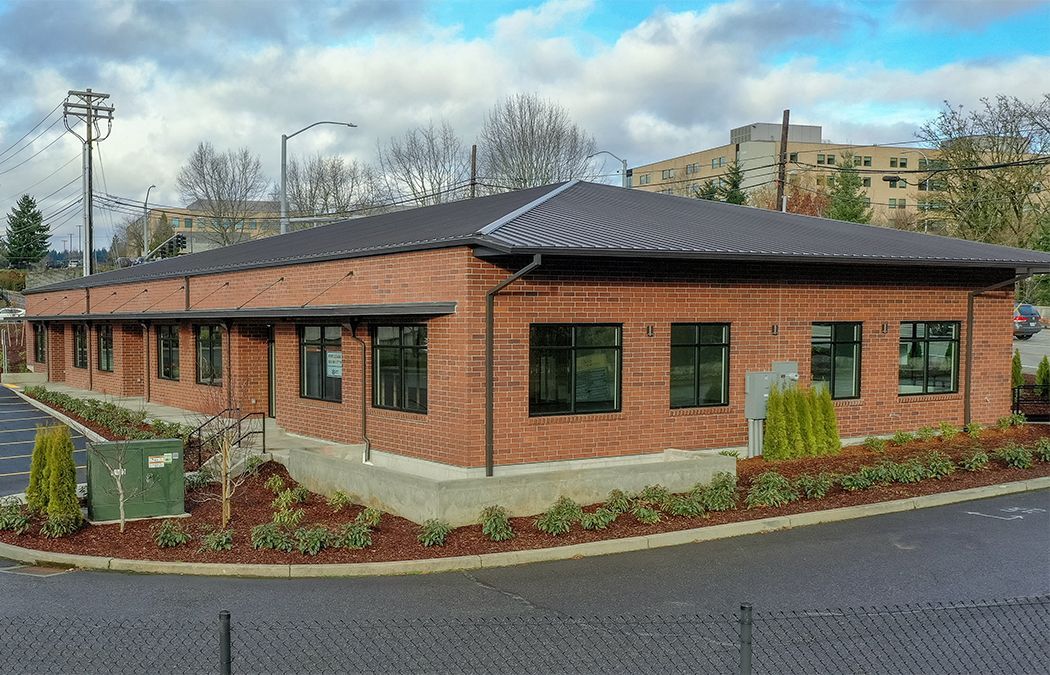 A large brick building with a lot of windows is sitting on the corner of a street.