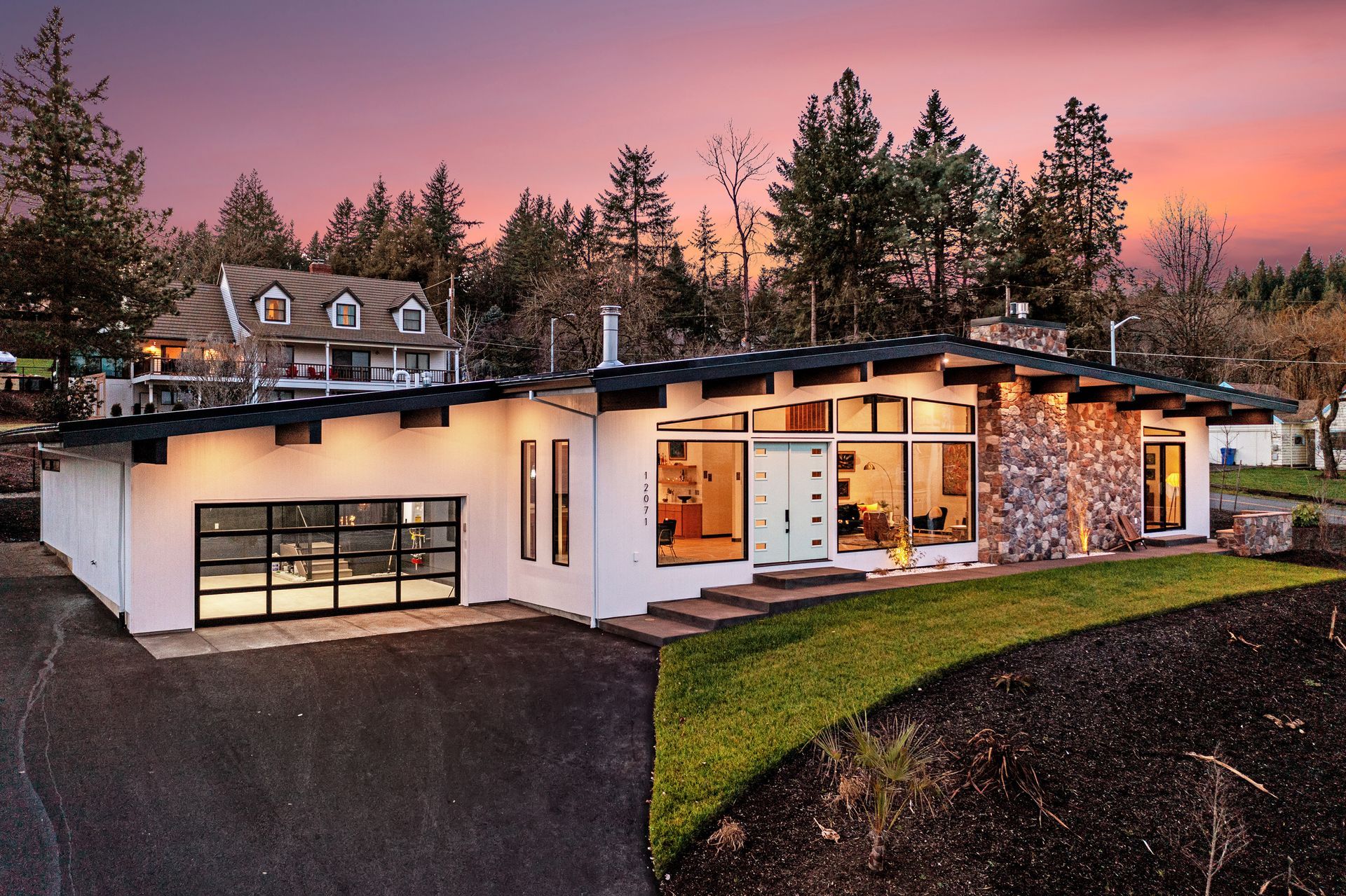 A green house with a porch and a brick walkway