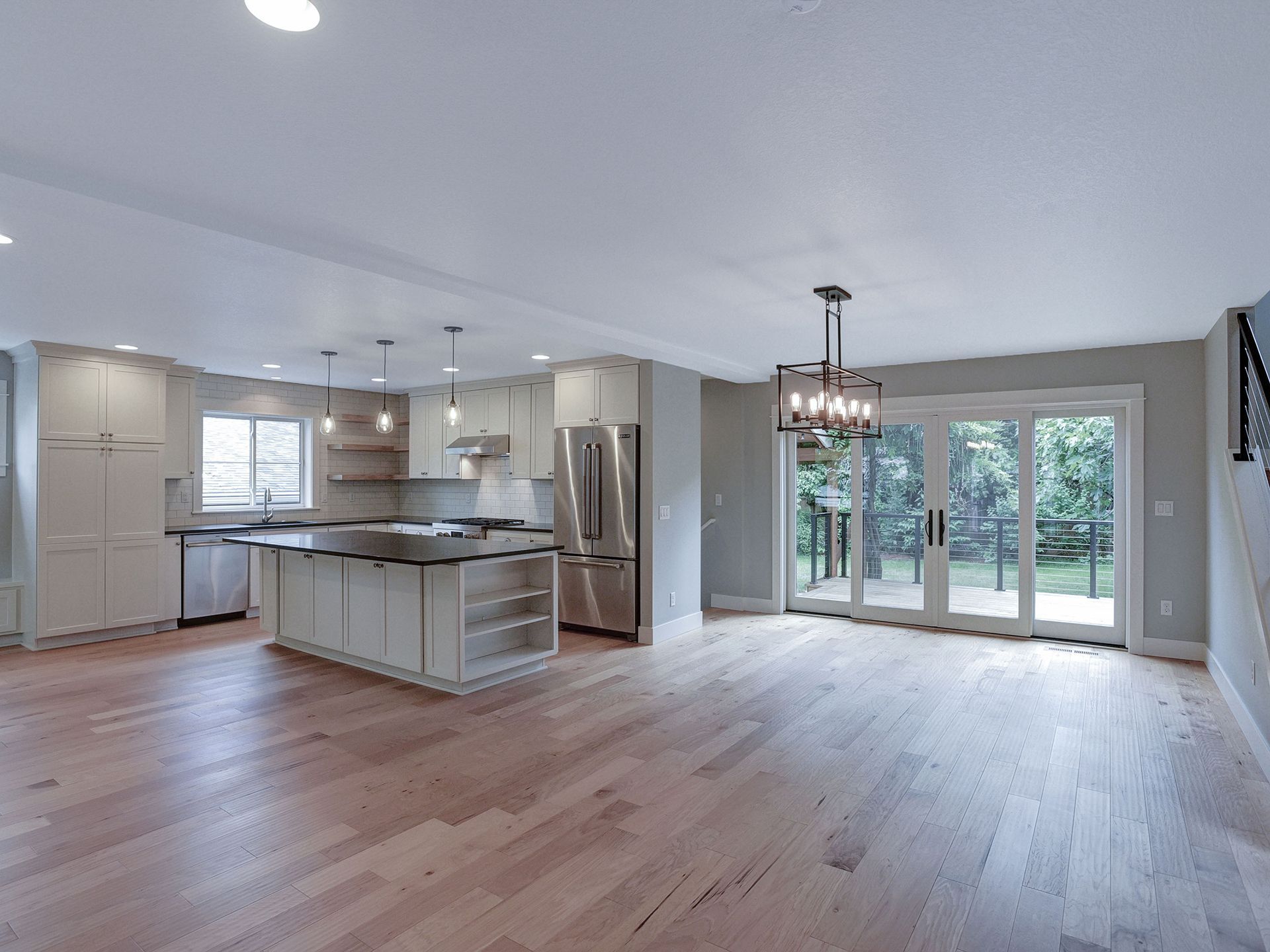 A large empty kitchen with hardwood floors and stainless steel appliances