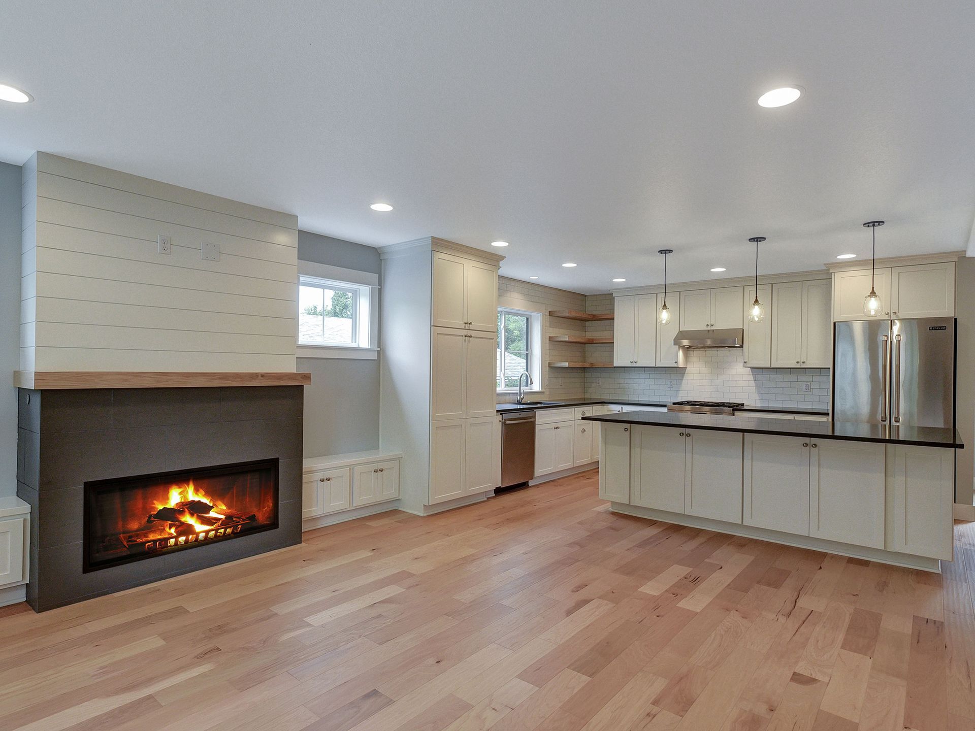 A room with a fireplace and a kitchen in the background