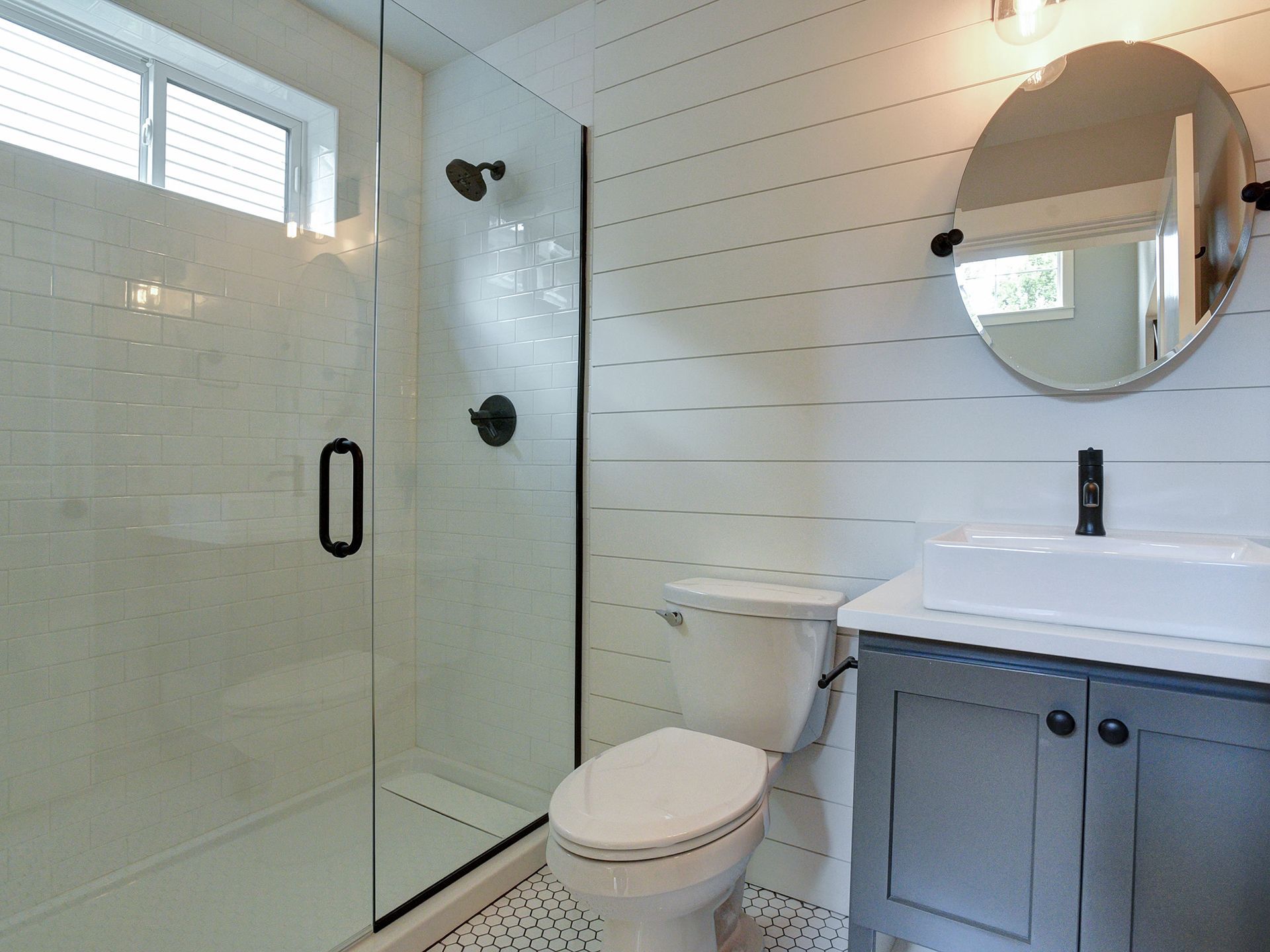 A bathroom with a toilet, sink, shower, and mirror