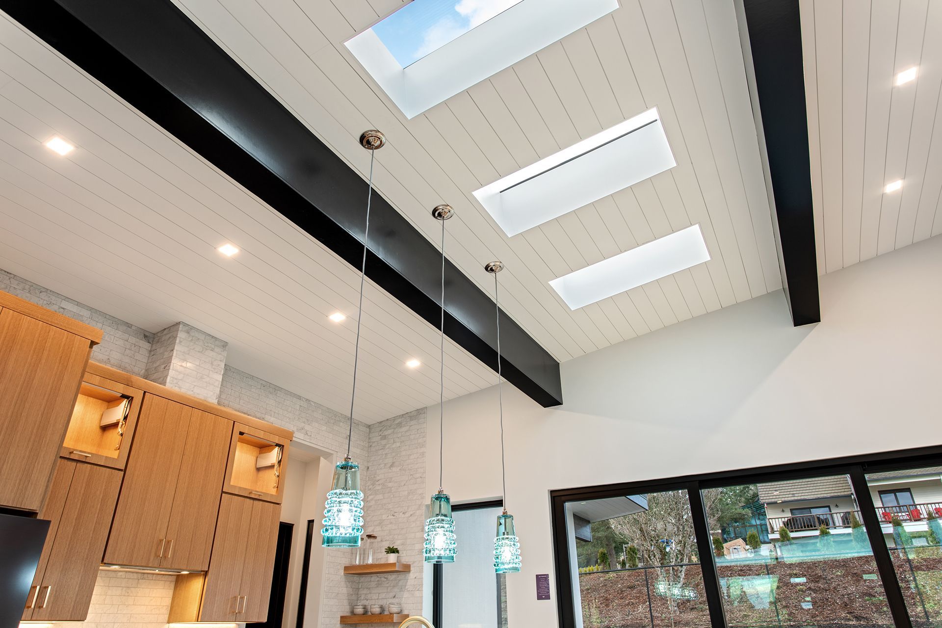 A kitchen with a skylight in the ceiling and a lot of windows
