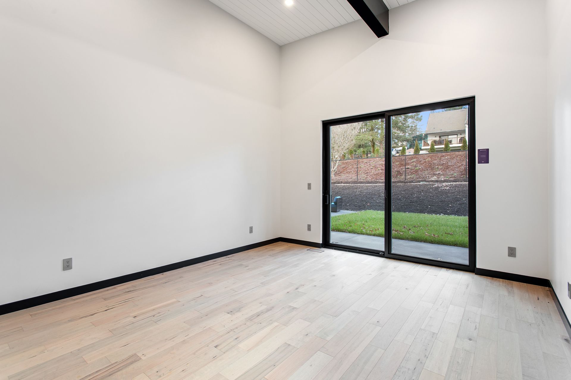 An empty room with hardwood floors and a sliding glass door