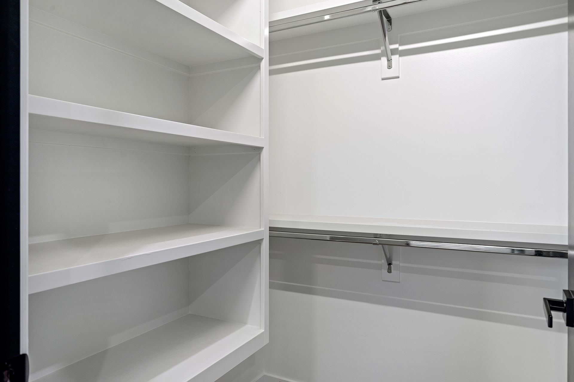 A walk-in closet with empty shelves and a hanging rail