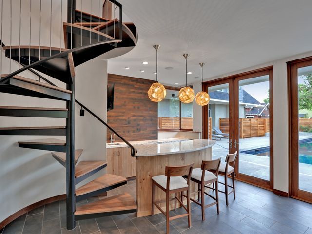 A kitchen bar beside a spiral staircase 