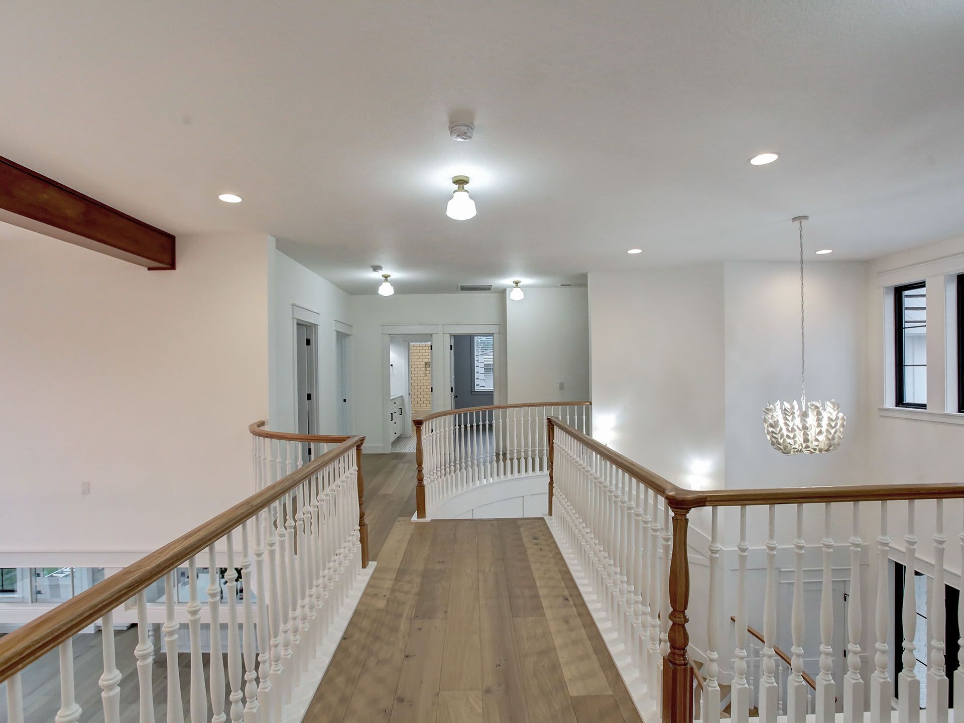 A hallway in a house with a wooden railing and a chandelier hanging from the ceiling