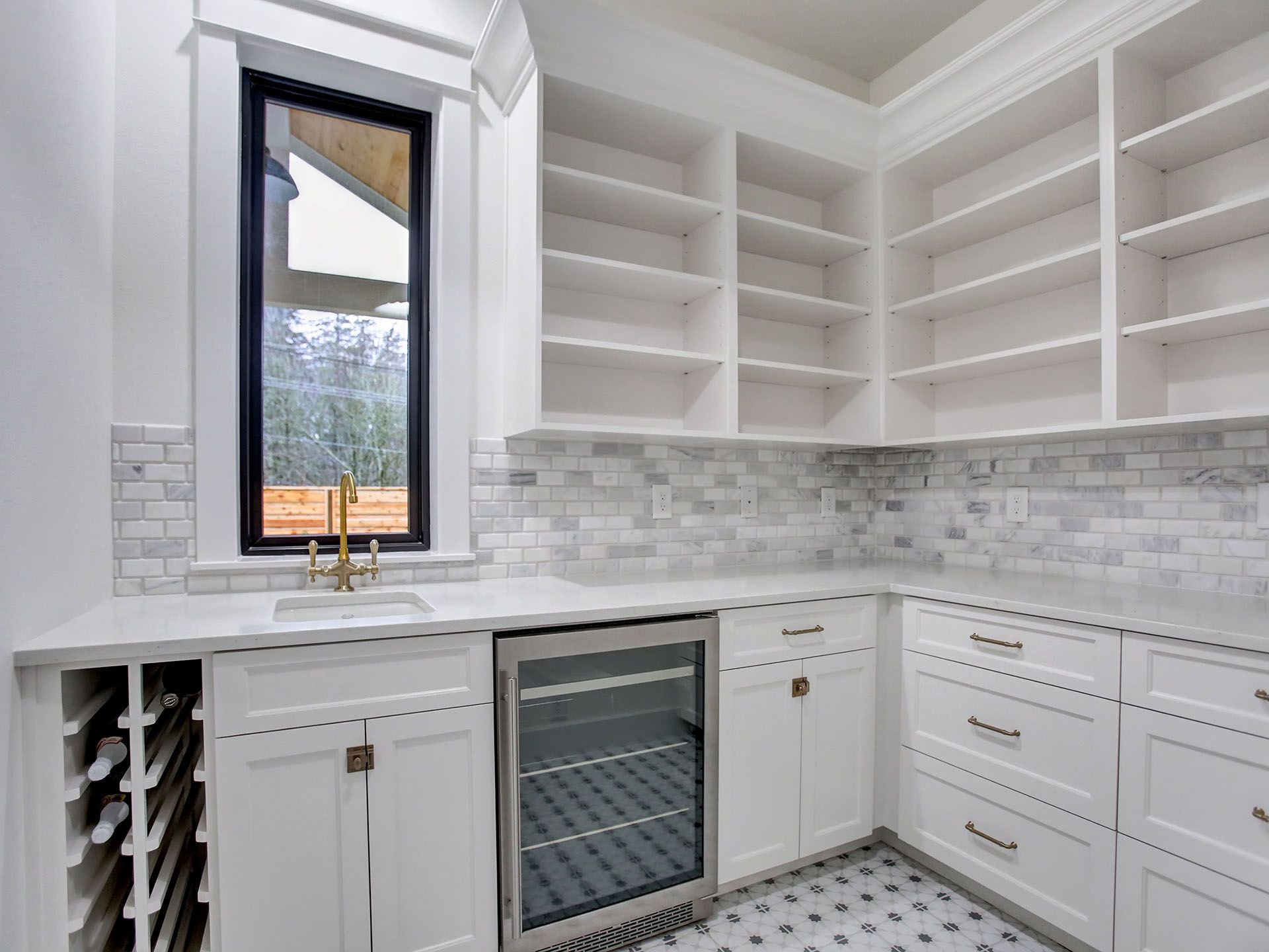 A kitchen with white cabinets and gray tiles