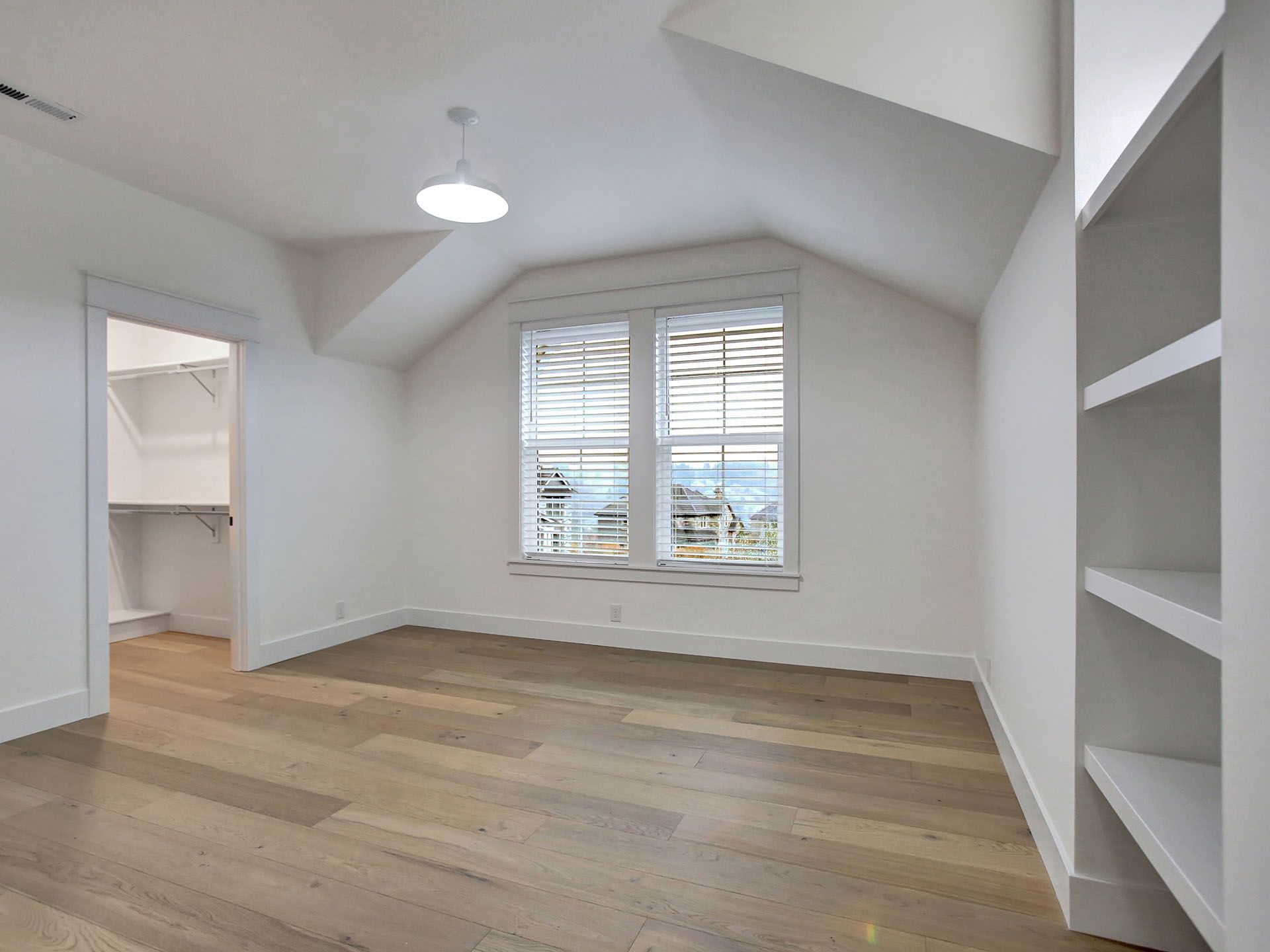 An empty room with hardwood floors and white walls