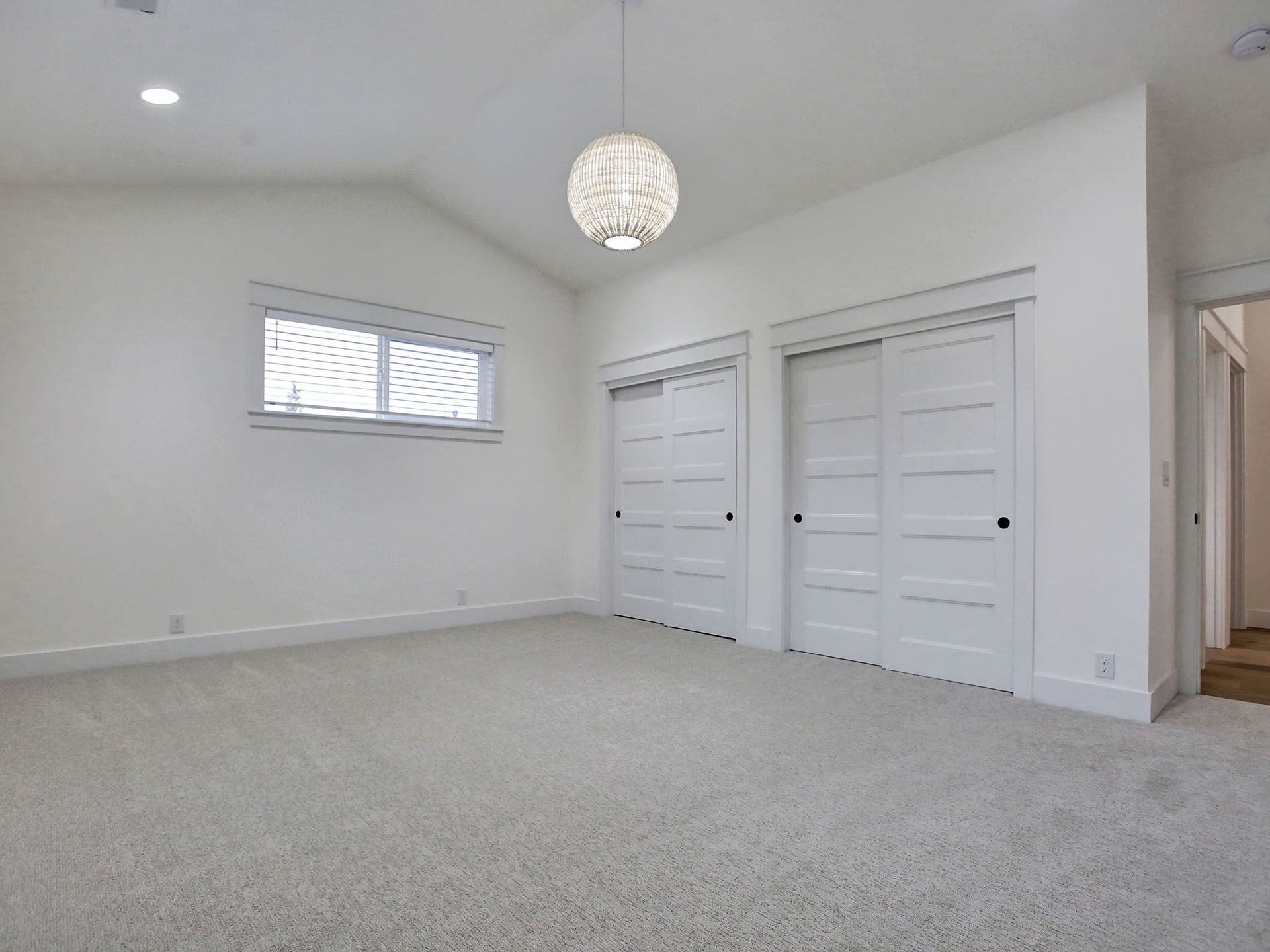 An empty bedroom with white walls and carpeted floors