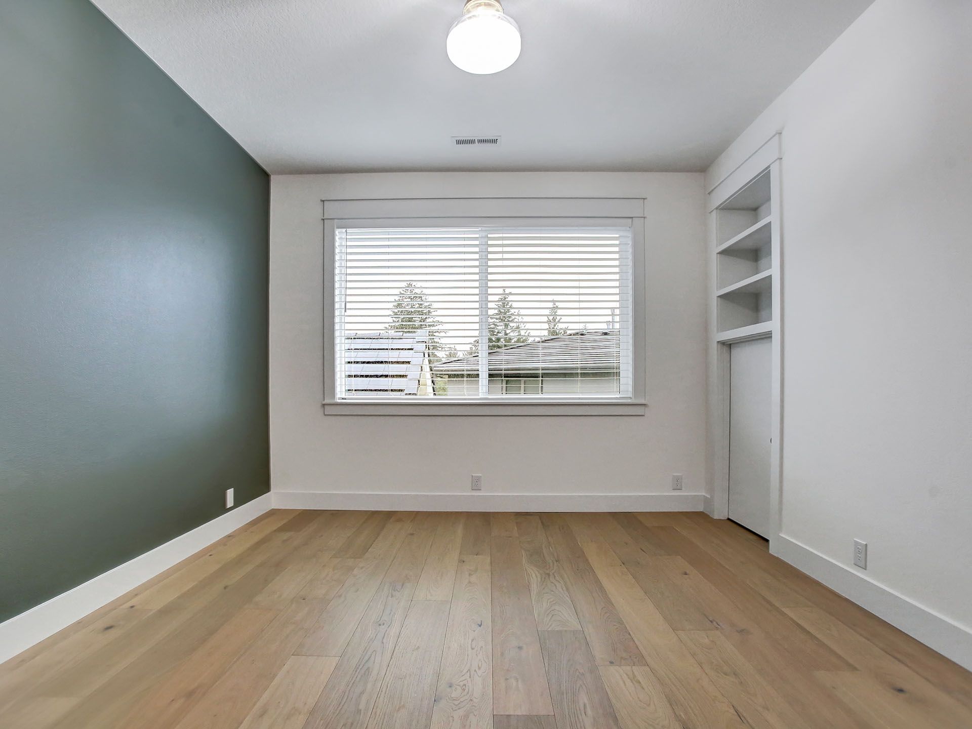 An empty room with hardwood floors and a dark gray wall