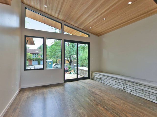 An empty living room with hardwood floors and wooden ceiling