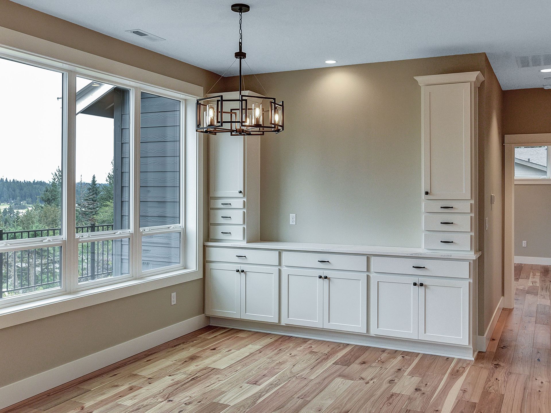 An empty room with hardwood floors and cabinets