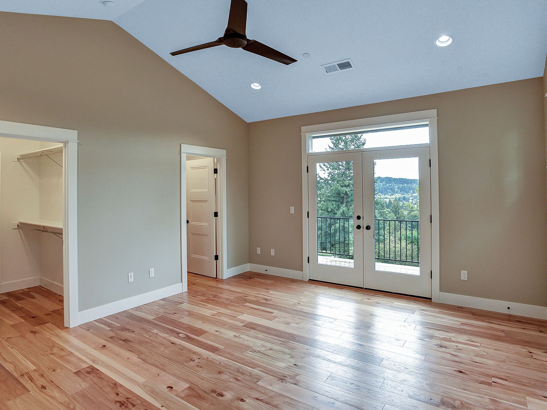 An empty room with hardwood floors and a ceiling fan