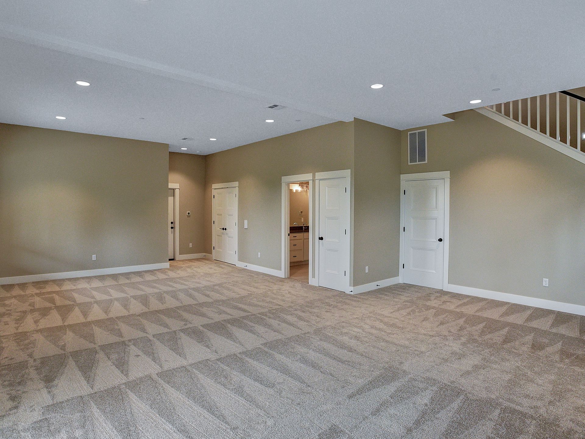 A large empty room with a staircase and a carpeted floor