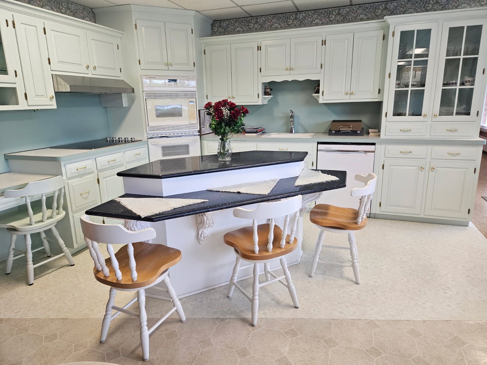 A kitchen with white cabinets and a large island in the middle.