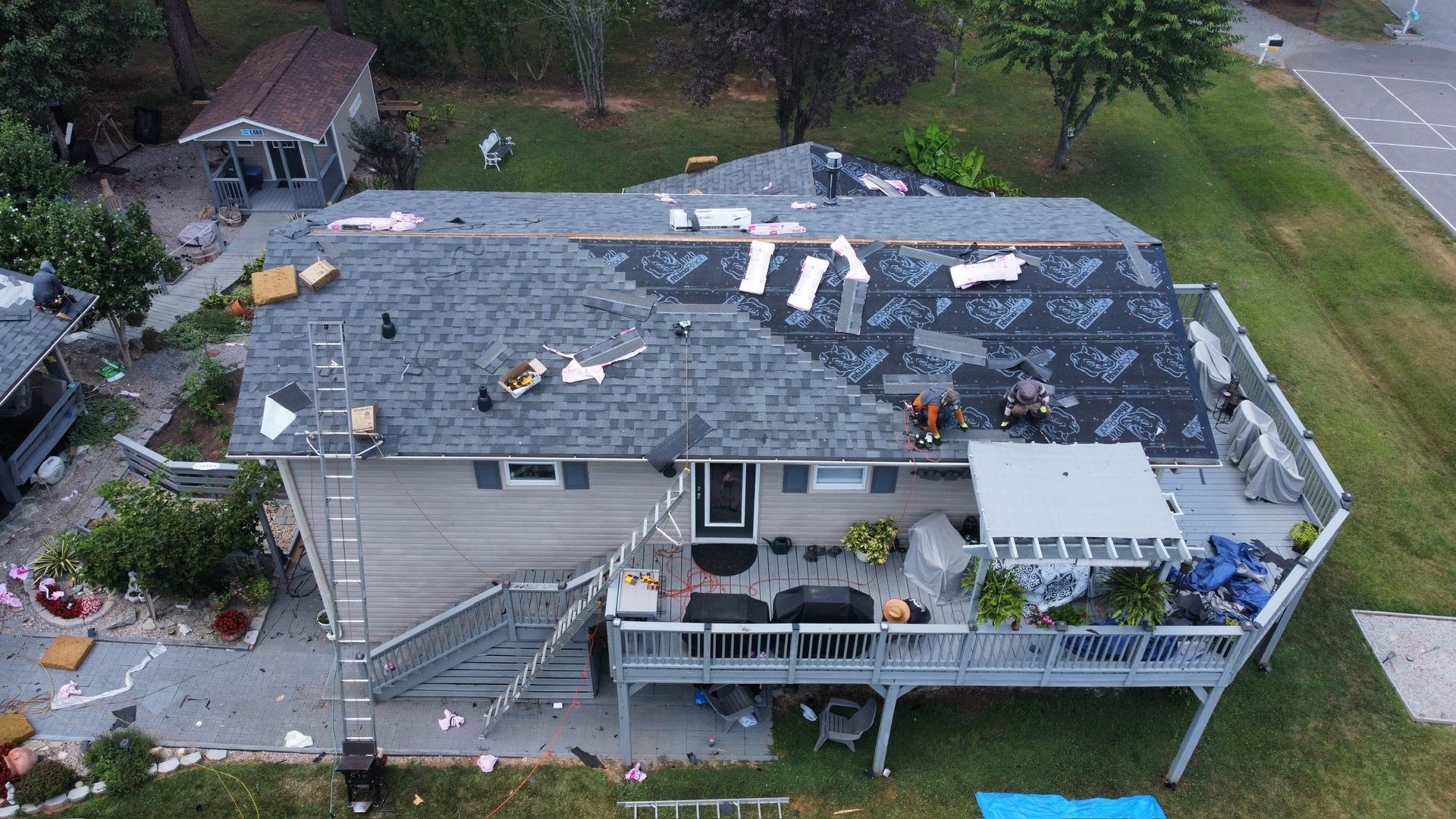 Aerial view of a house with a partially damaged roof and scattered debris after a storm