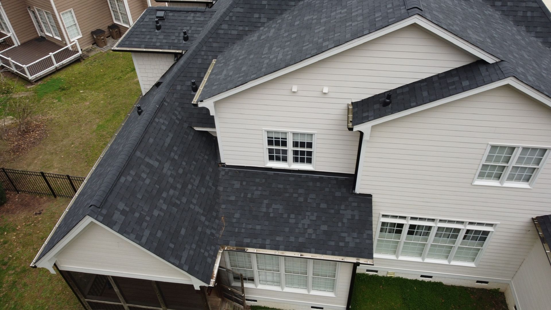 Aerial view of a suburban house with a dark gray roof and white siding.
