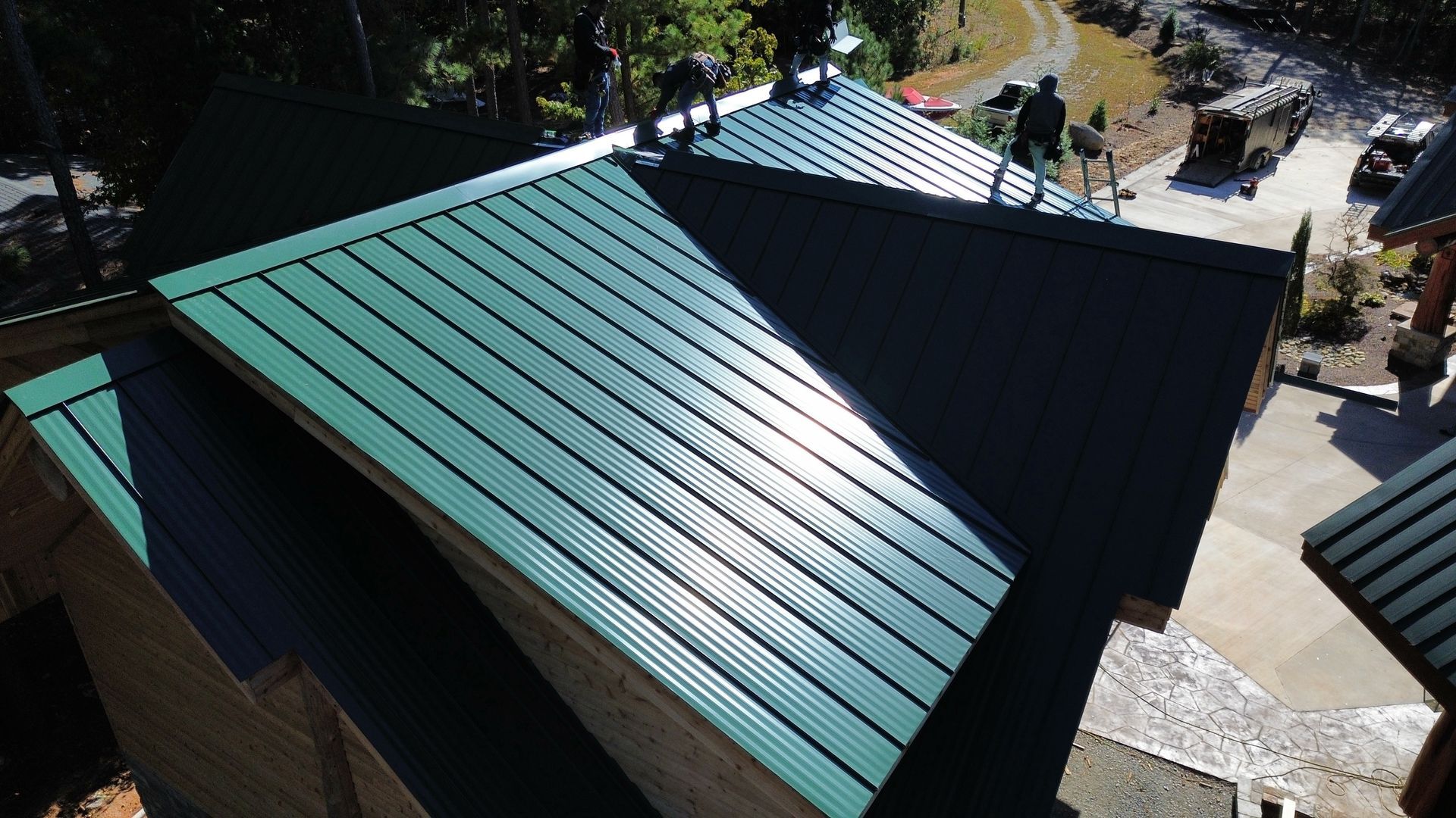 Green metal roofs on small buildings, viewed from above in a wooded outdoor setting.