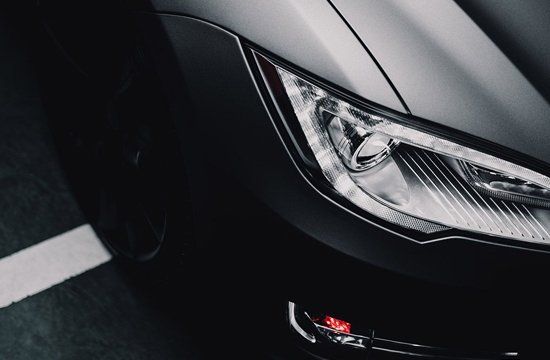 A close up of a car 's headlight in a parking lot