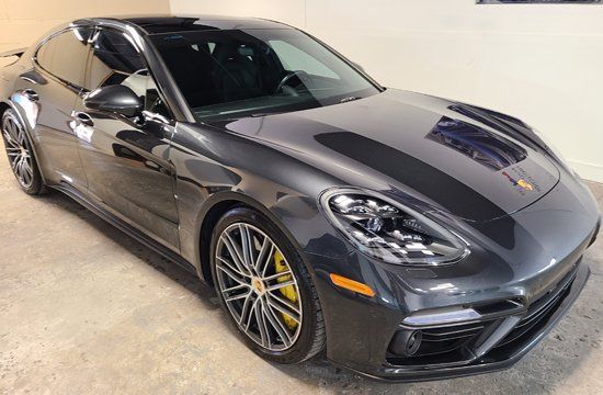 A gray porsche panamera is parked in a garage