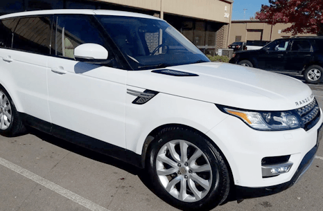 A white range rover sport is parked in a parking lot