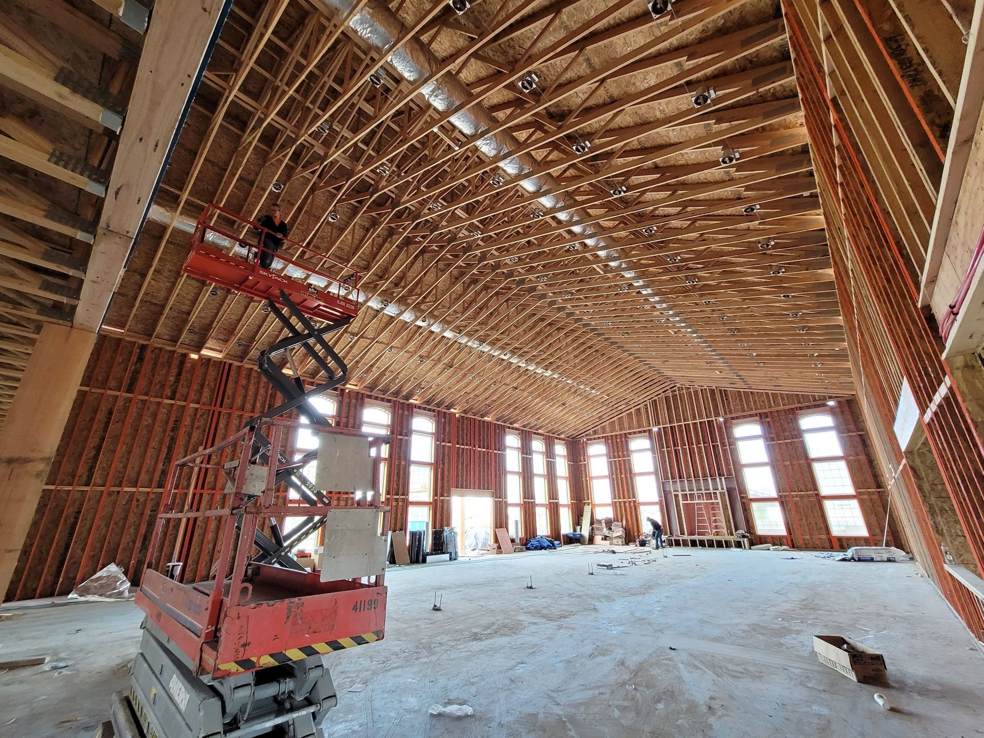 A scissor lift is sitting in the middle of a large room under construction.