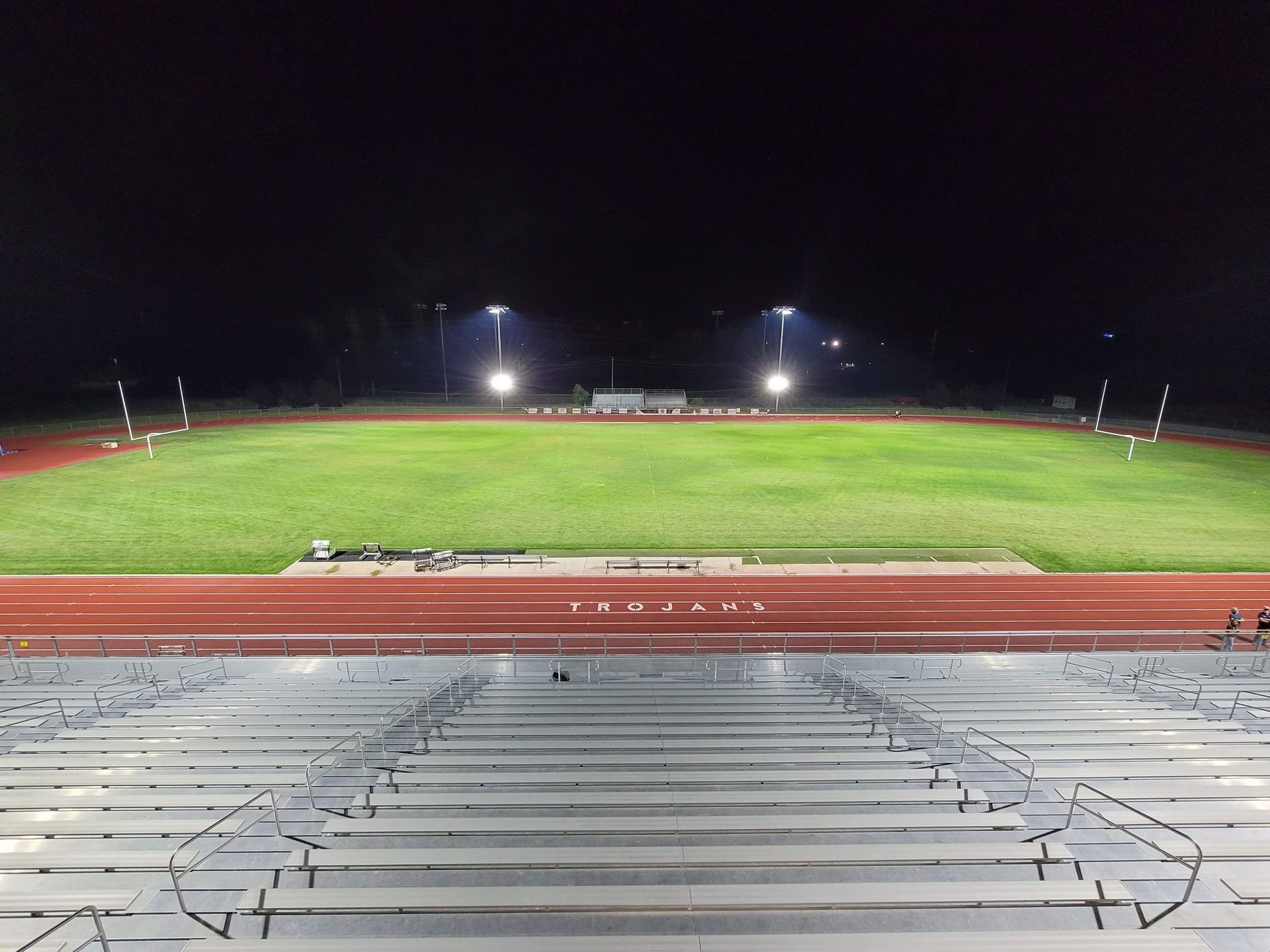 A stadium with a track and bleachers at night