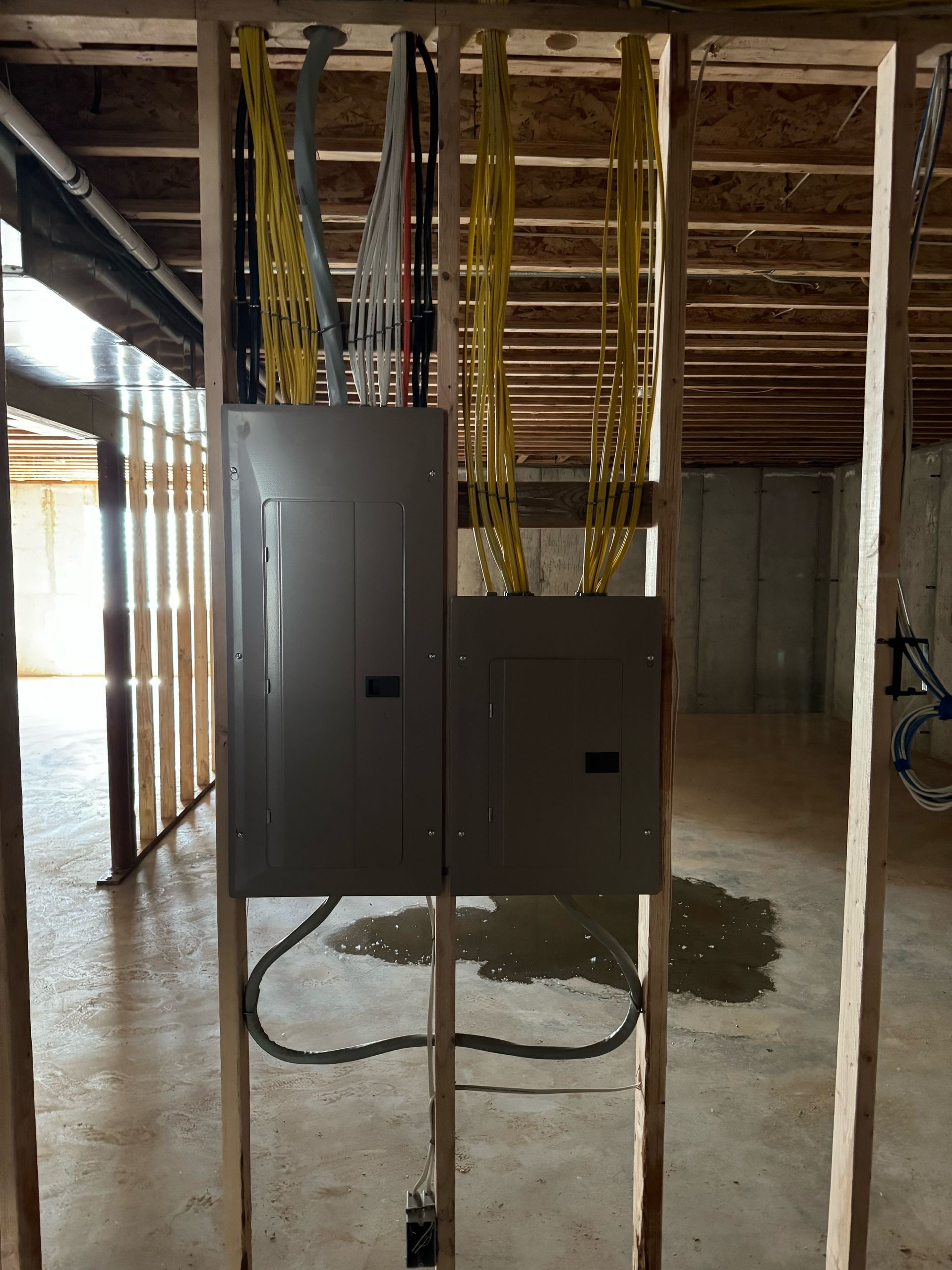An electrical box is hanging from the ceiling in a basement