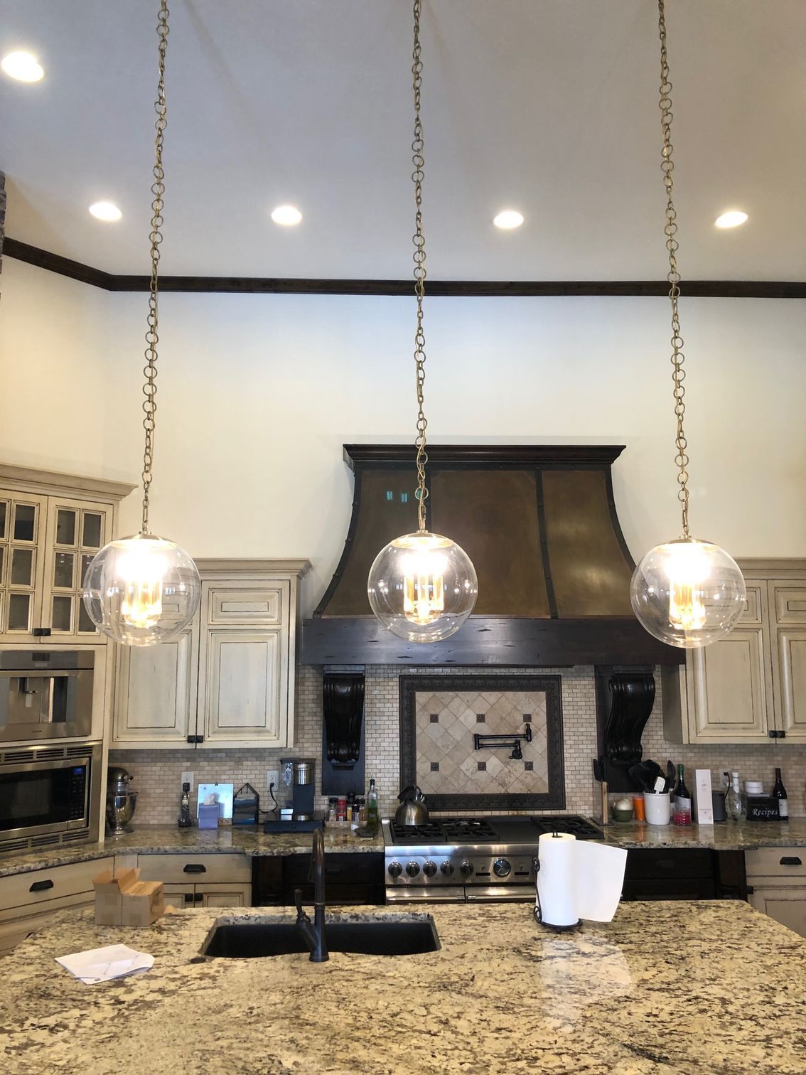 A kitchen with a sink, stove, and pendant lights hanging from the ceiling.