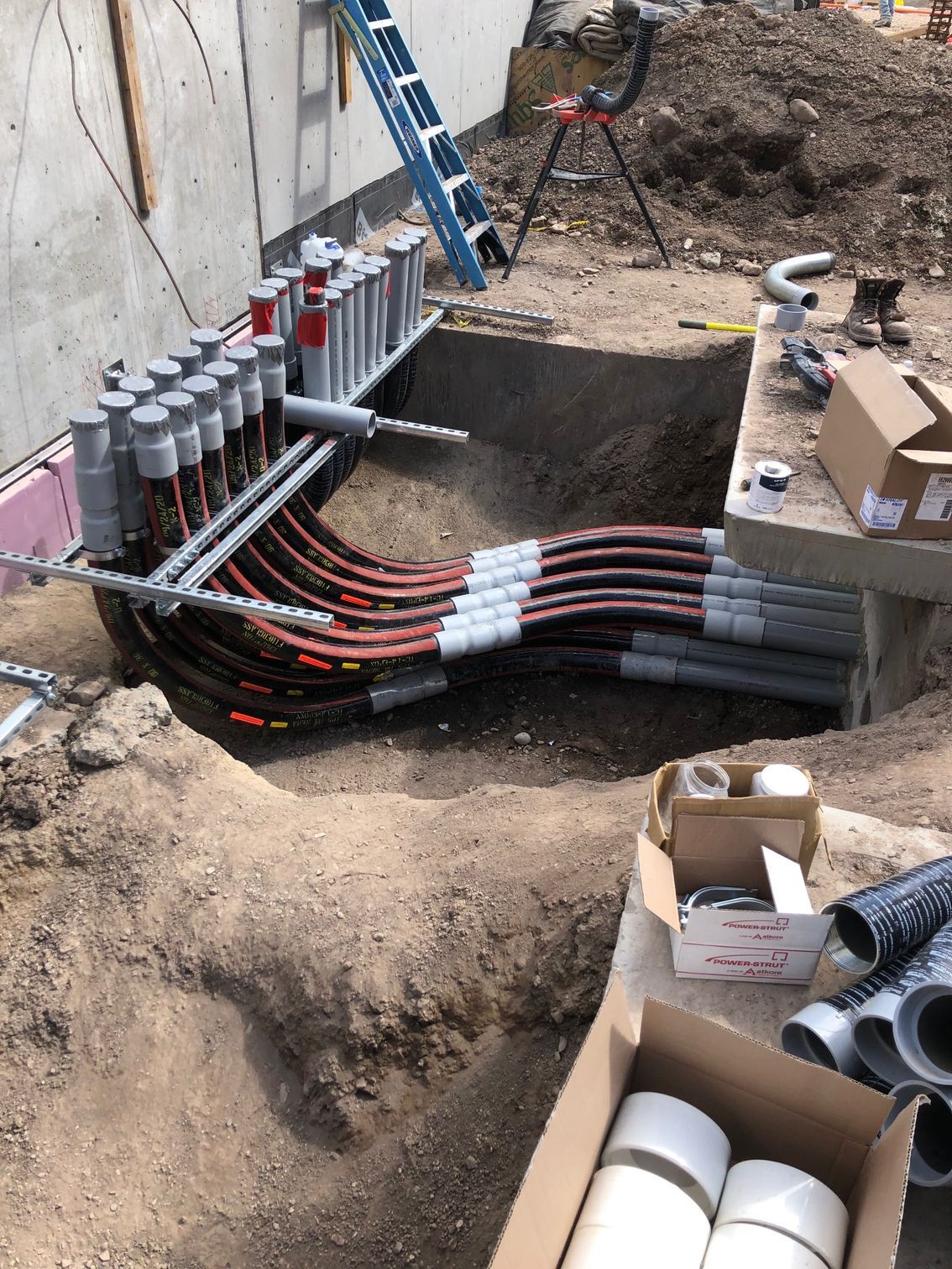 A bunch of electrical wires are being installed in a hole in the ground.