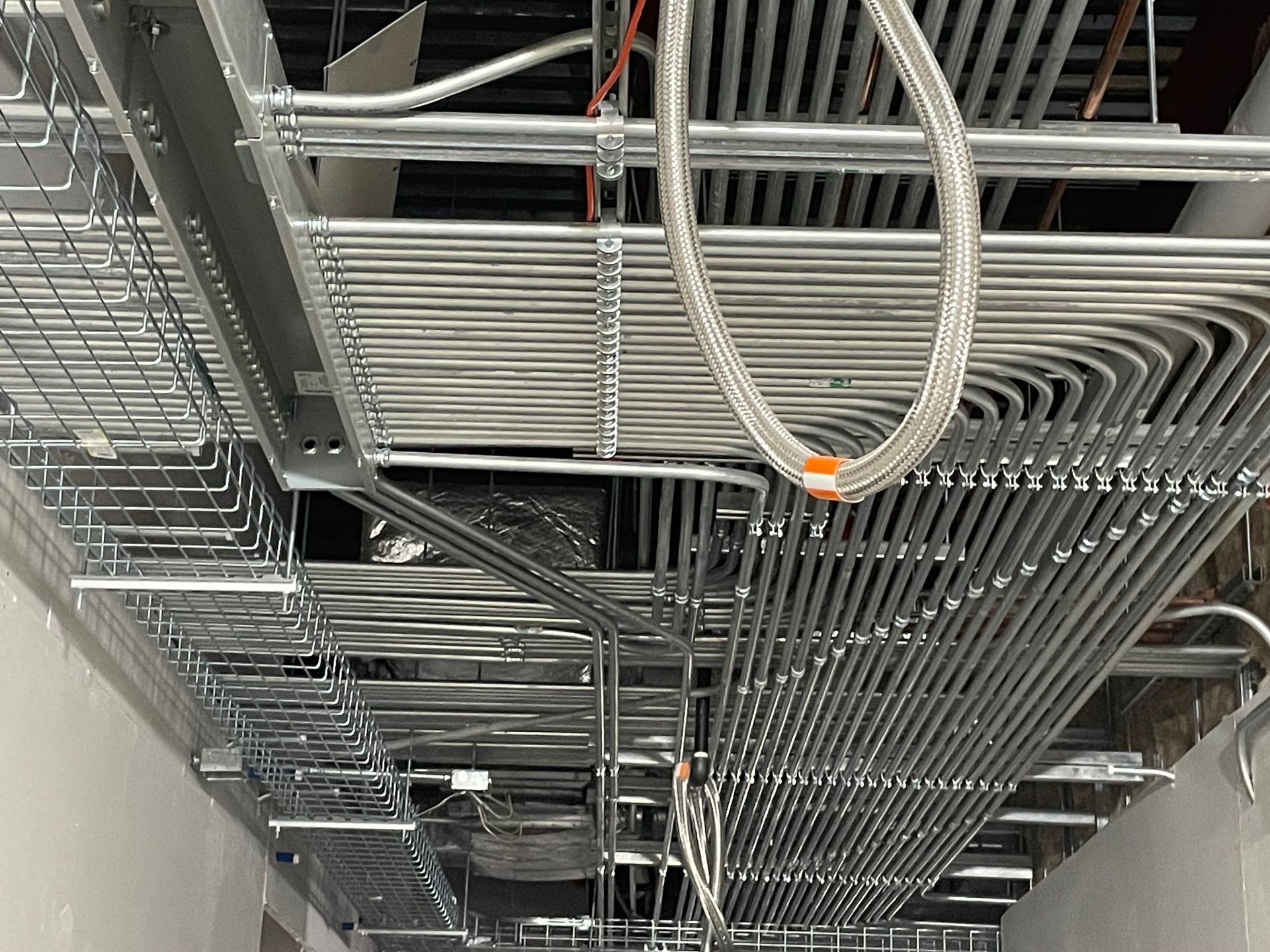 A bunch of metal pipes are hanging from the ceiling of a building.
