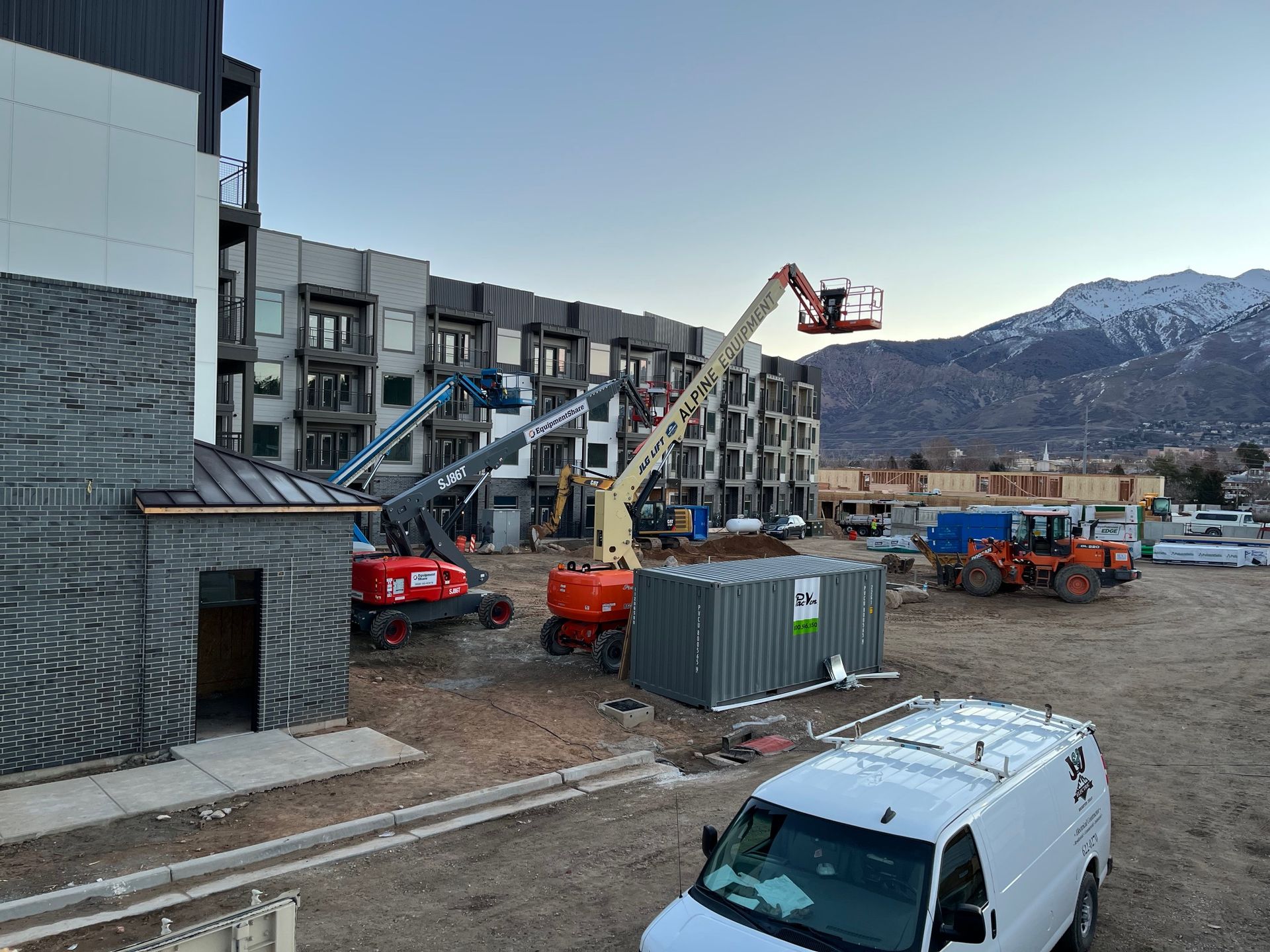 A white van is parked in front of a building under construction.