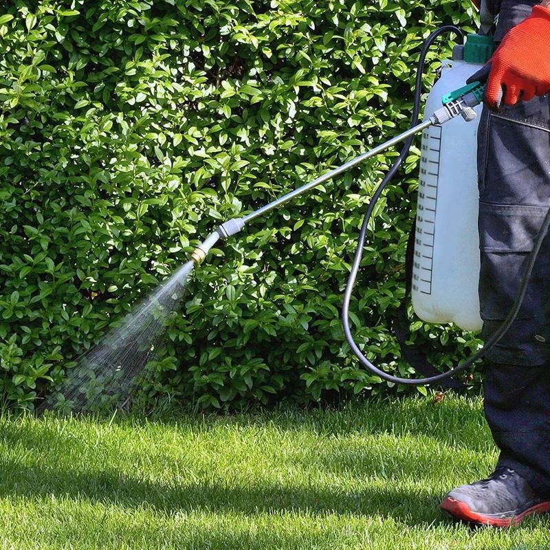 A person is spraying a lawn with a sprayer.