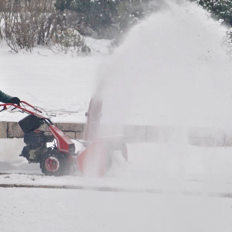 A person is using a snow blower to clear snow from a driveway